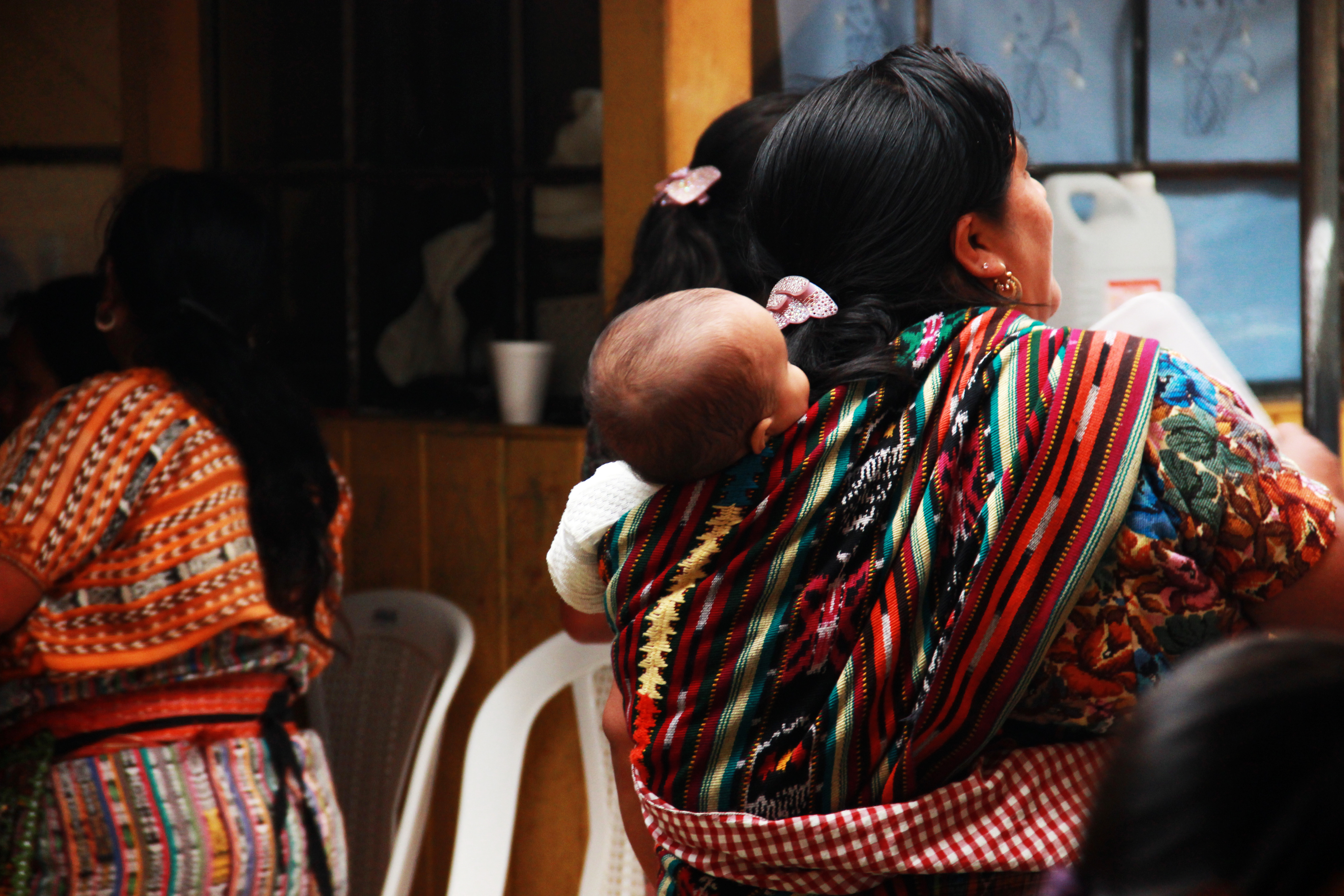 Mujeres guatemaltecas en reunión comunitaria con un bebé en perraje