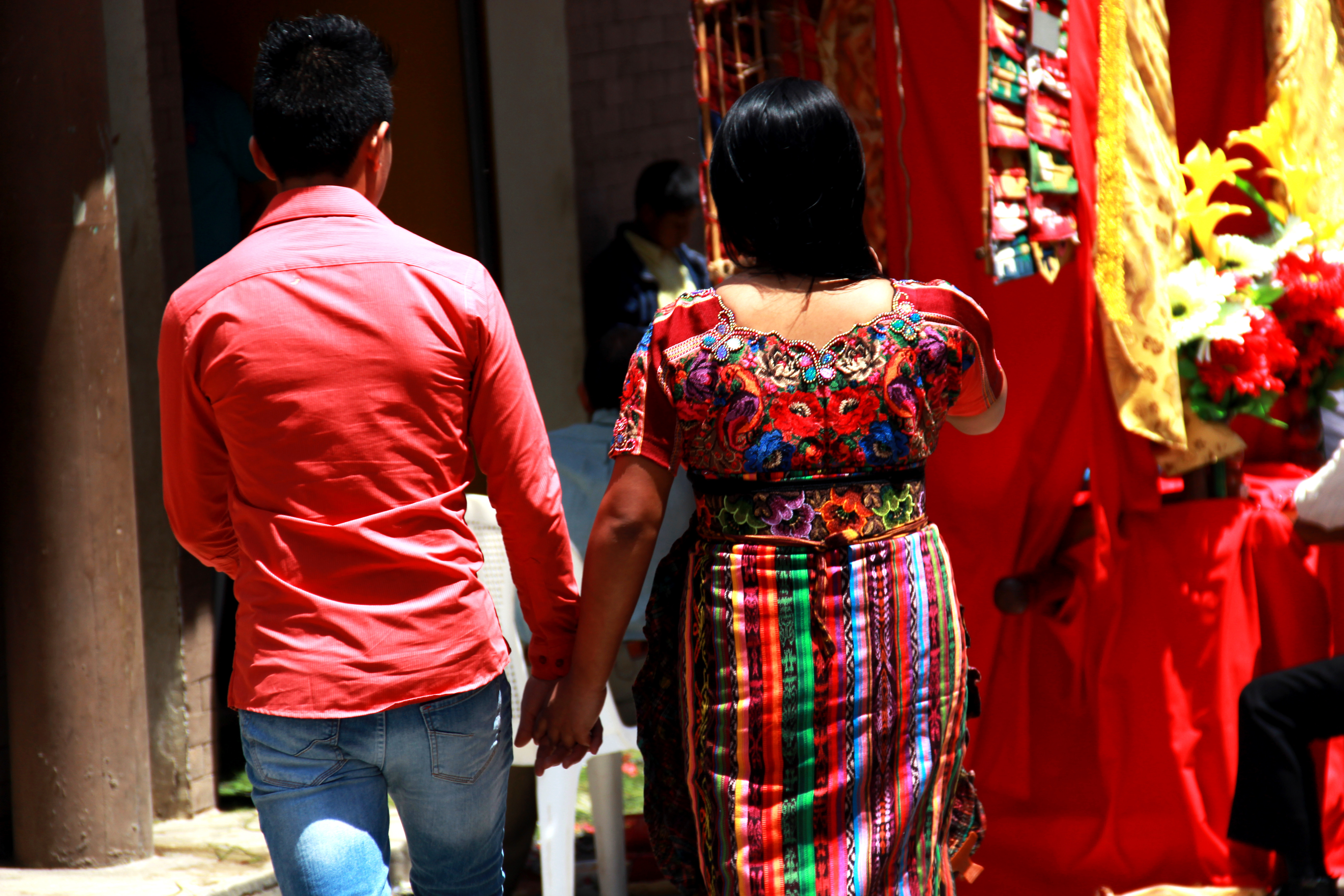Pareja guatemalteca tomada de la mano vistiendo huipil tradicional