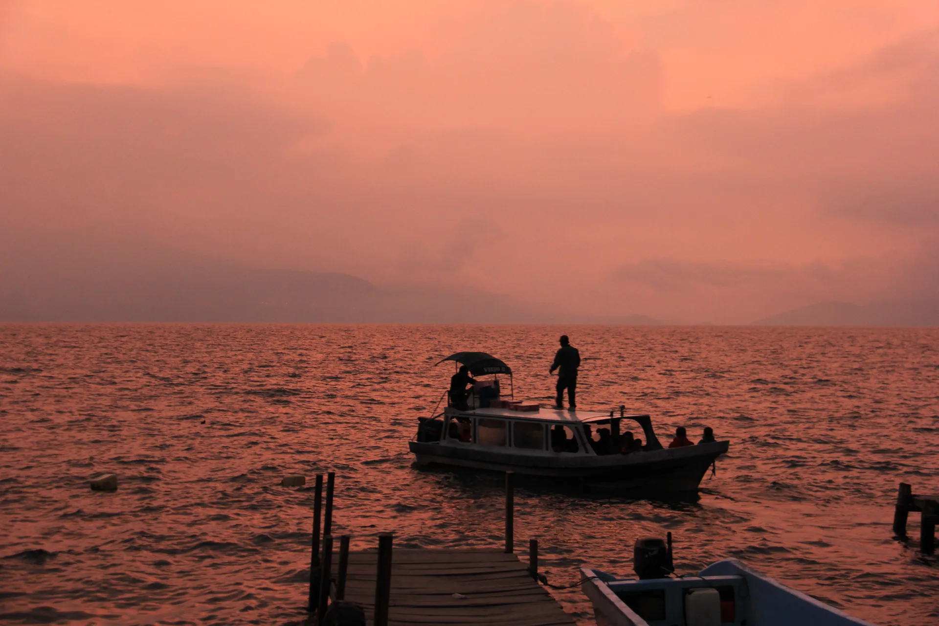 Atardecer en el Lago de Atitlán con una lancha y personas navegando